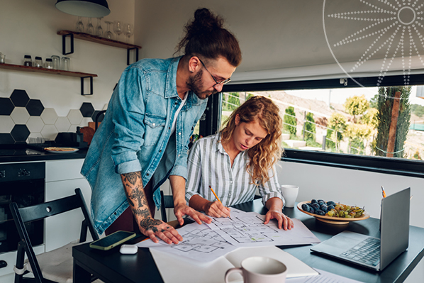 a couple in their 30s looking at paperwork at their kitchen table